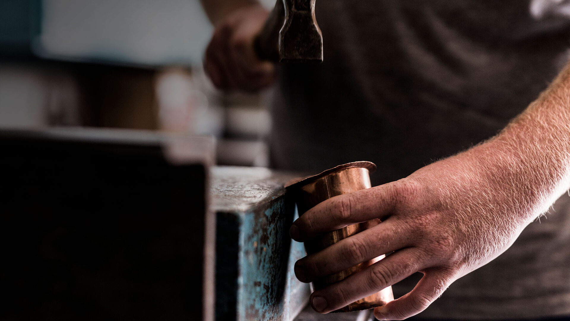 Ein Mann hält einen Hammer und ein Stück Holz in der Hand, bereit zum Arbeiten.